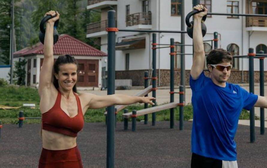 Two athletes performing overhead kettlebell holds during RCMP training program workout
