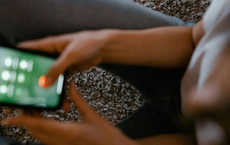 Person using a smartphone while sitting indoors, representing RCMP cadet phone access, communication rules, and personal device usage during Depot training.