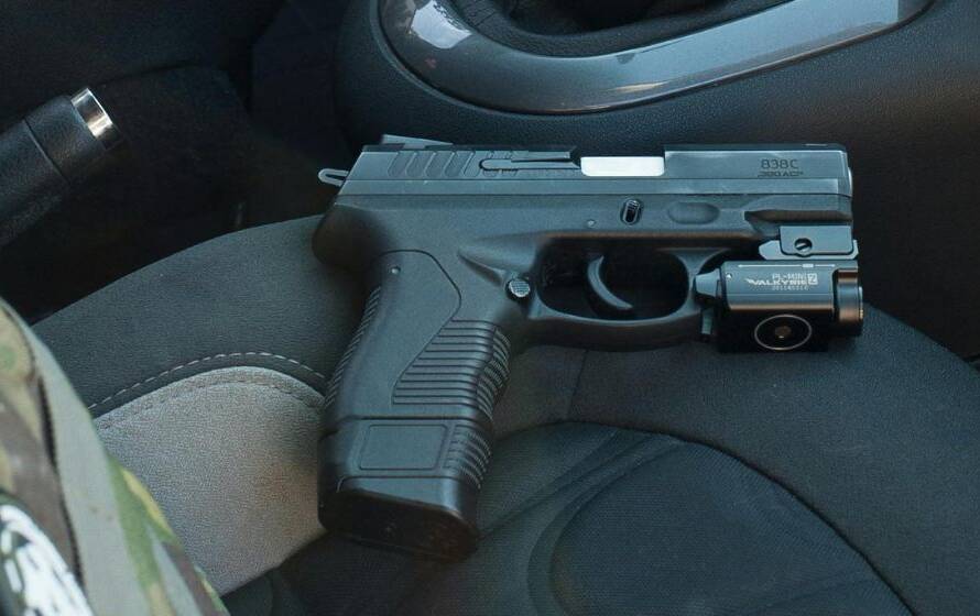 Handgun placed on the front seat of a vehicle beside tactical gear, representing Canadian firearm transportation and legal transport regulations.