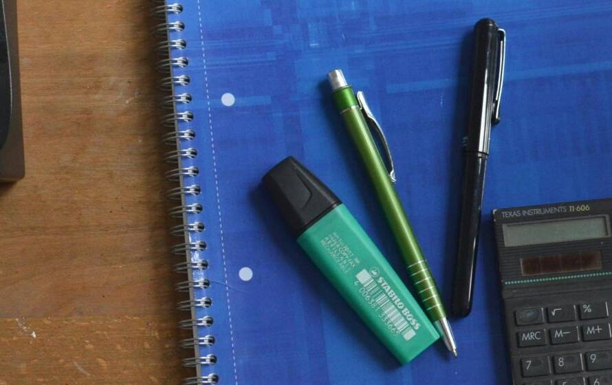 Notebook, calculator, pens, and office supplies on a desk representing RCMP cadet pay, budgeting, training expenses, and financial planning during the police application process.
