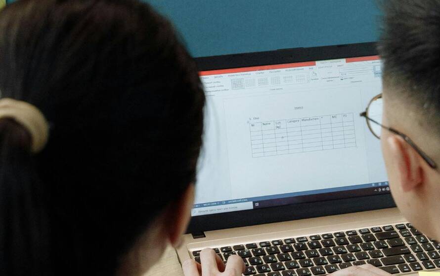 Two people working on a laptop reviewing digital documents and spreadsheets, representing RCMP application processing, paperwork review, and administrative preparation.