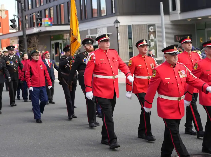 Canadian military colour guard carrying national and regimental flags during a Remembrance Day parade, linked to what happens if you fail the RCMP entrance exam.