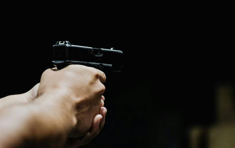 Close-up of a person aiming a handgun during firearms training, representing RCMP Depot firearms instruction and police use-of-force preparation.